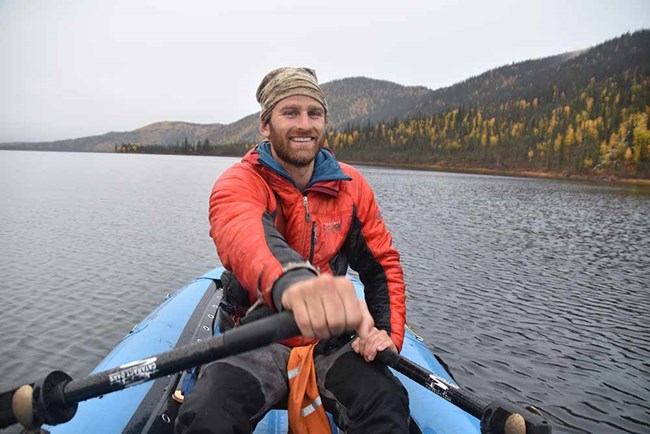 A man rowing an inflatable raft on a river.