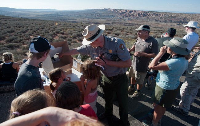 A Park Ranger teaching visitors about viewing an eclipse without looking directly into the sun. The Park Ranger is using a projection tool to view the eclipse.