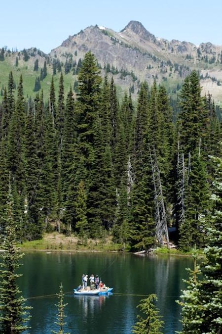 Several people on a small inflated boat in the middle of a subalpine lake.