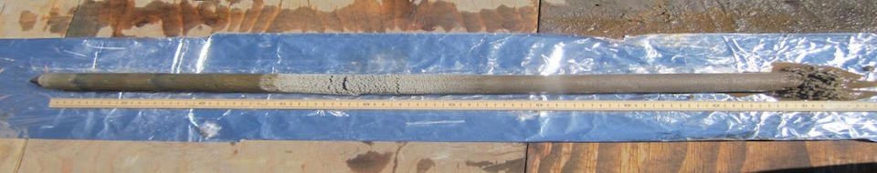 Lake sediment core A long narrow core of sediment lies next to a long ruler on a sheet of tin foil.
