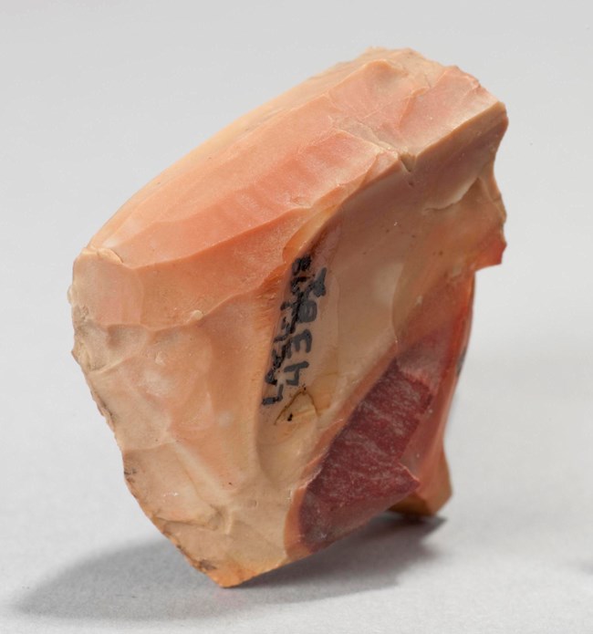 Image of an archeological artifact, a peach colored stone with lines, arrow points. Image of an archeological artifact, a peach colored stone with lines, arrow points.