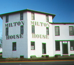 Milton House White, stone house with green painted words that say Milton House.