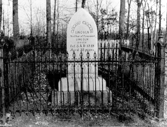 Headstone behind iron fence.