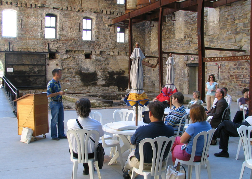 People sitting in chairs and a man presenting.