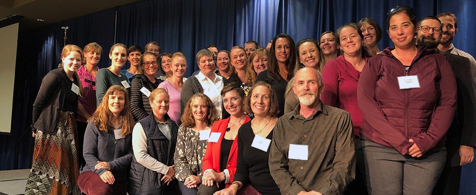 The 2019 Women and Leadership Symposium group. A group of women and men stand in a group on a stage.