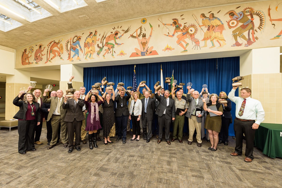 Congratulations to Director's Award winners! large group of people hold awards up in a large conference room