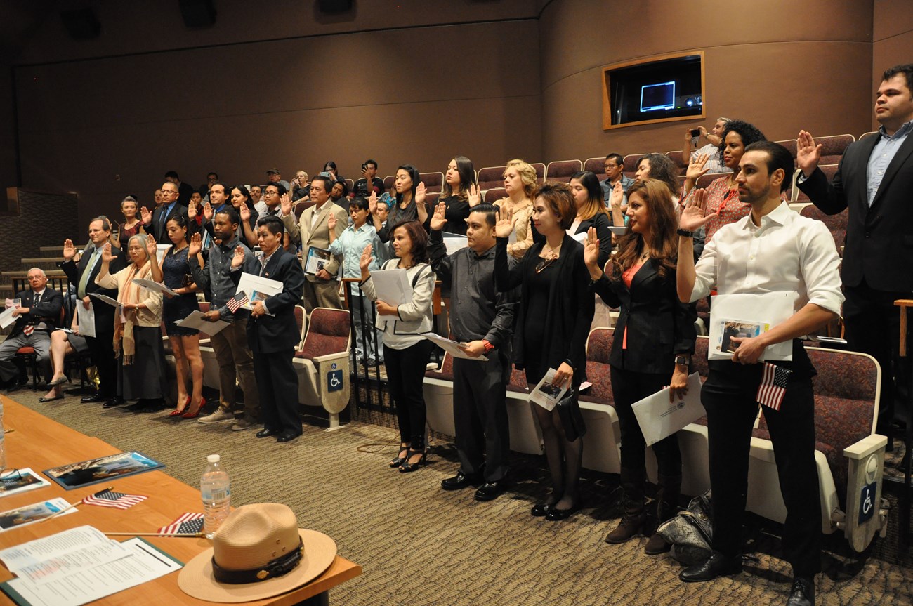 24 new citizens raise their right hands during naturalization ceremony in Hoover Dam auditorium.