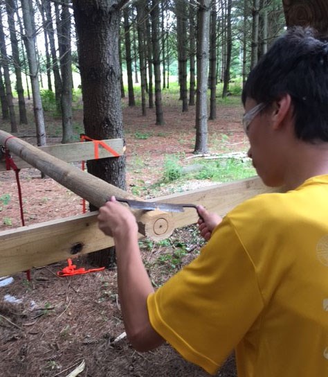 Nick Gilson, Hartzog Award recipient working on a volunteer project. Boy outside holding a tool onto a wooden post.
