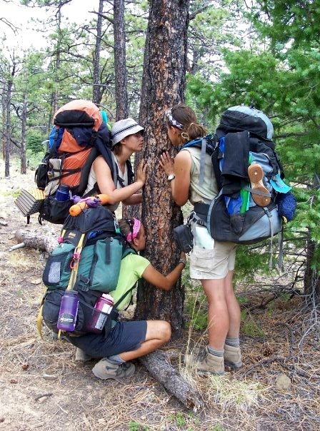 Outdoor Adventure Young women hug a tree in a nature exercise on the trail