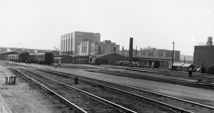 B&W photo of railroad tracks with trains and the white Union Station in the background.