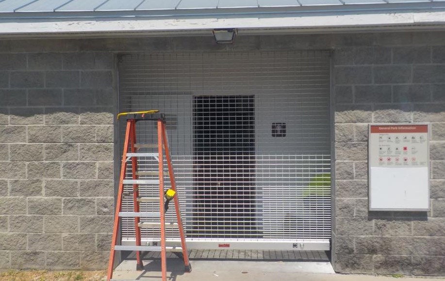 A concrete building with a pull-down, grill gate, across the doorway opening. A concrete building with a pull-down, grill gate, across the doorway opening.