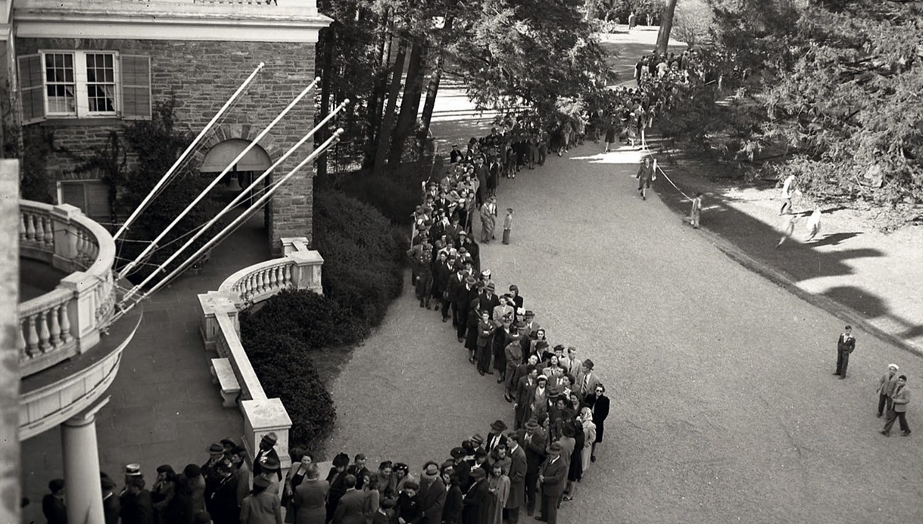 A long line of people waiting to enter a house.
