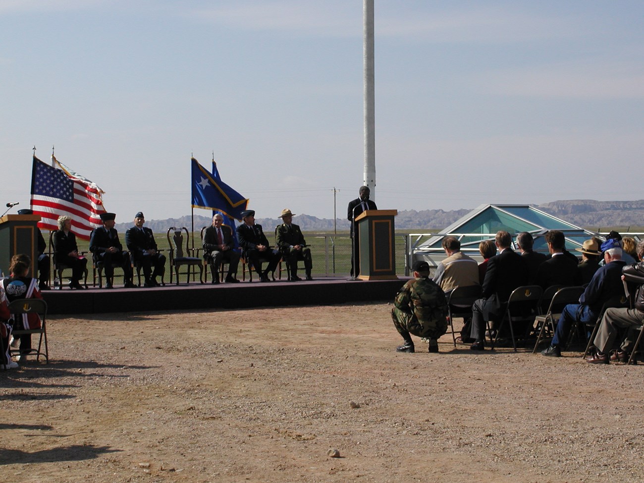 A man stands at a dais in a prairie landscape