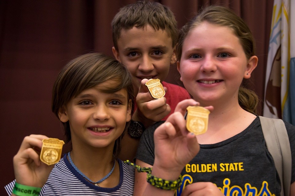 Three children wearing Junior Paleontologist booklets