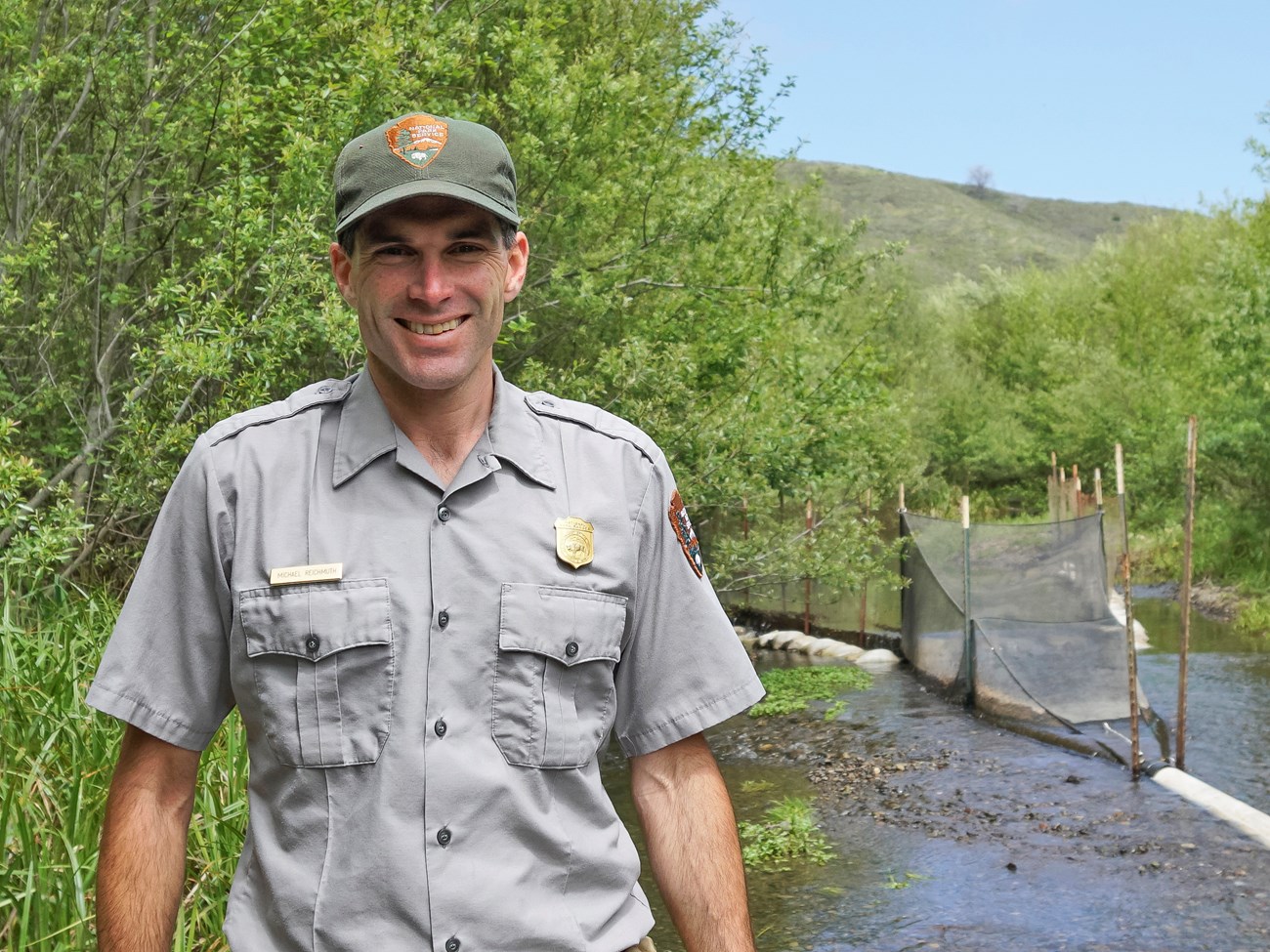 Fisheries biologist Michael Reichmuth poses by creek with smolt trap.