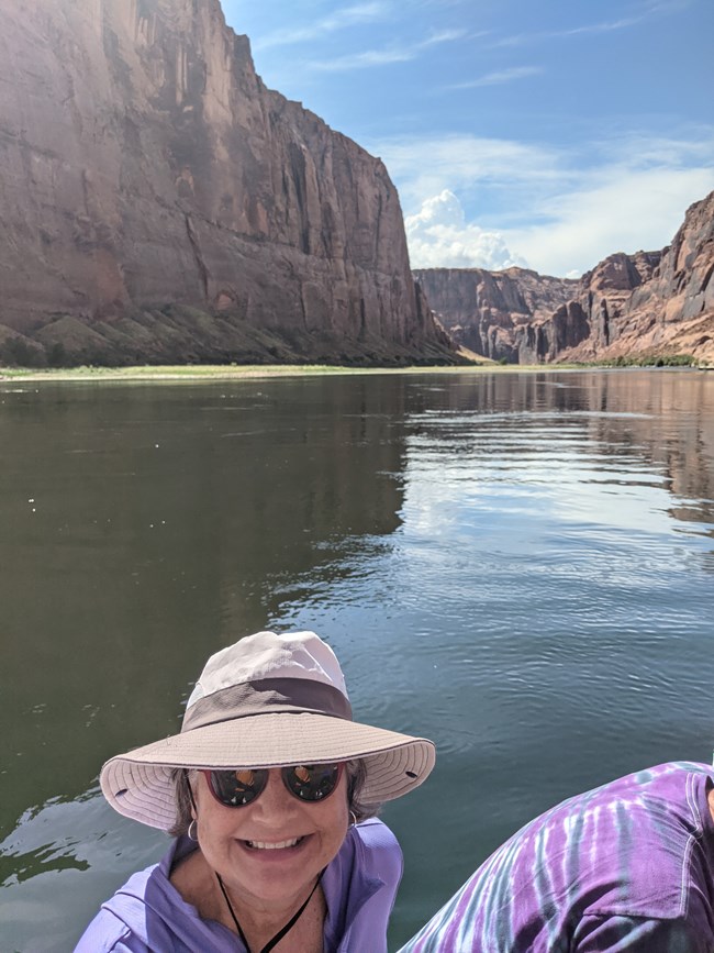 Deb Gardecki A person on small motorized watercraft on a river surrounded by tall canyon walls.