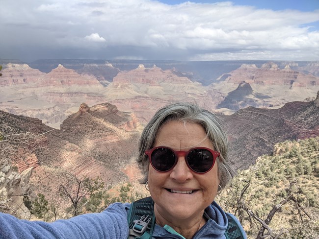 Deb Gradecki A person takes a selfie in front of a canyon filled lanscape.