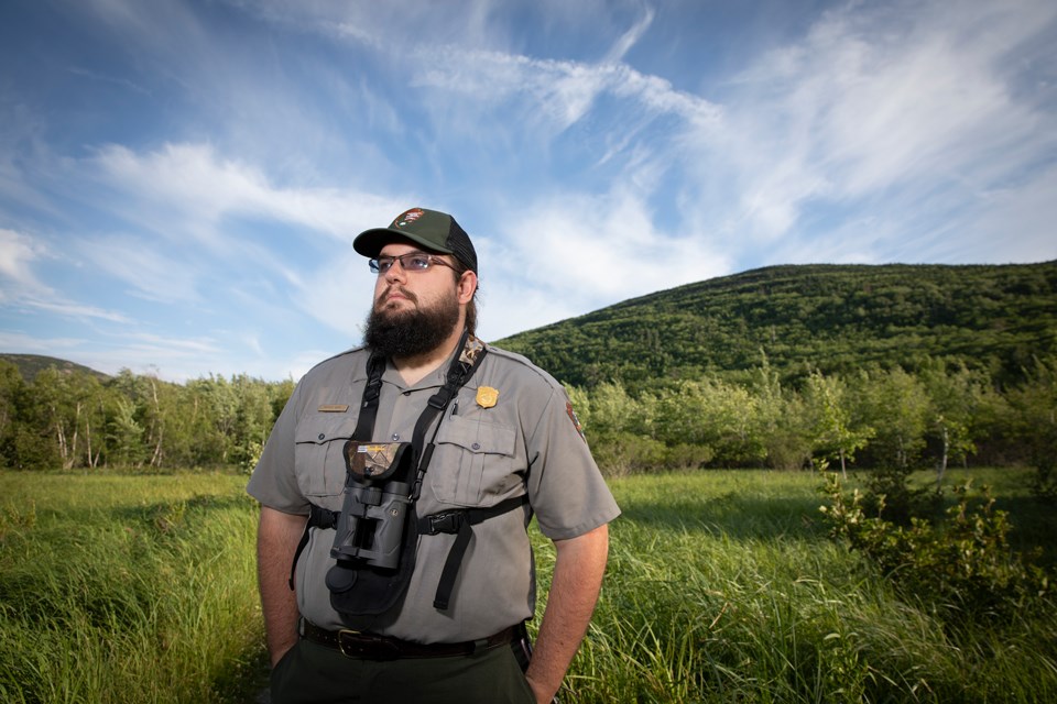 Bearded ranger wearing ball cap and binoculars