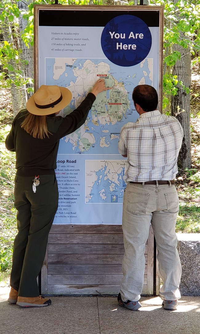 Park Ranger points to destinations on a map with a visitor watching