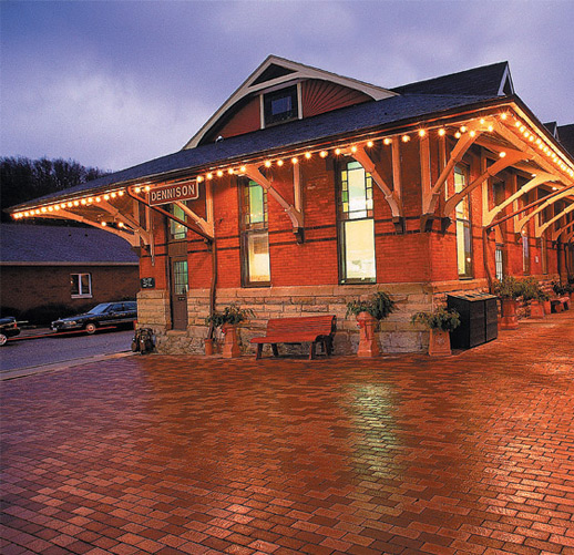 Brick building with string lights near a brick sidewalk.