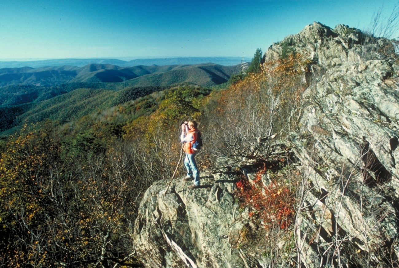 person standing on rocky point with mountains in the distance