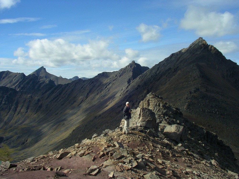 person standing on rocky point with mountains in the distance