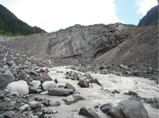 A gray colored river flowing out from a rocky glacier