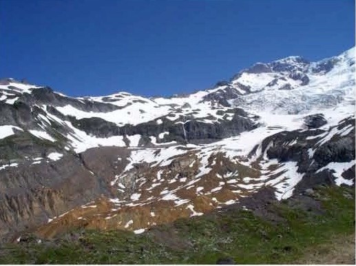 A brown snow covered glacier nestled in a rocky valley