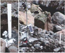 A small solar panel sitting above a rocky surface