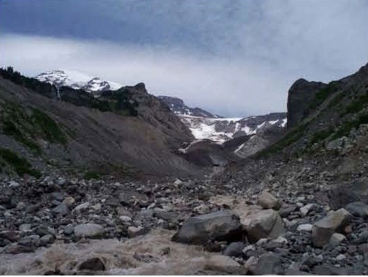 A gray colored river flowing out from a rocky glacier