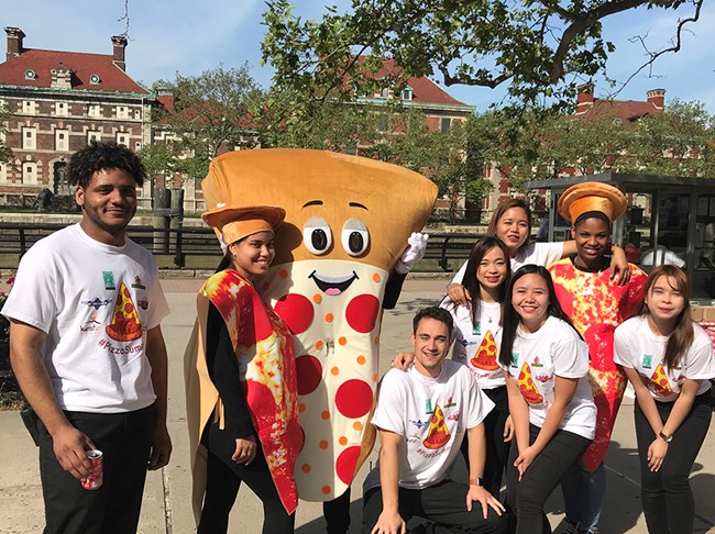 People pose with someone dressed as a giant slice of pizza