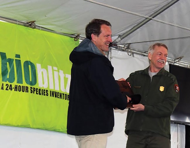 The director of the park service presents an award to the national geographic society for the bioblitz