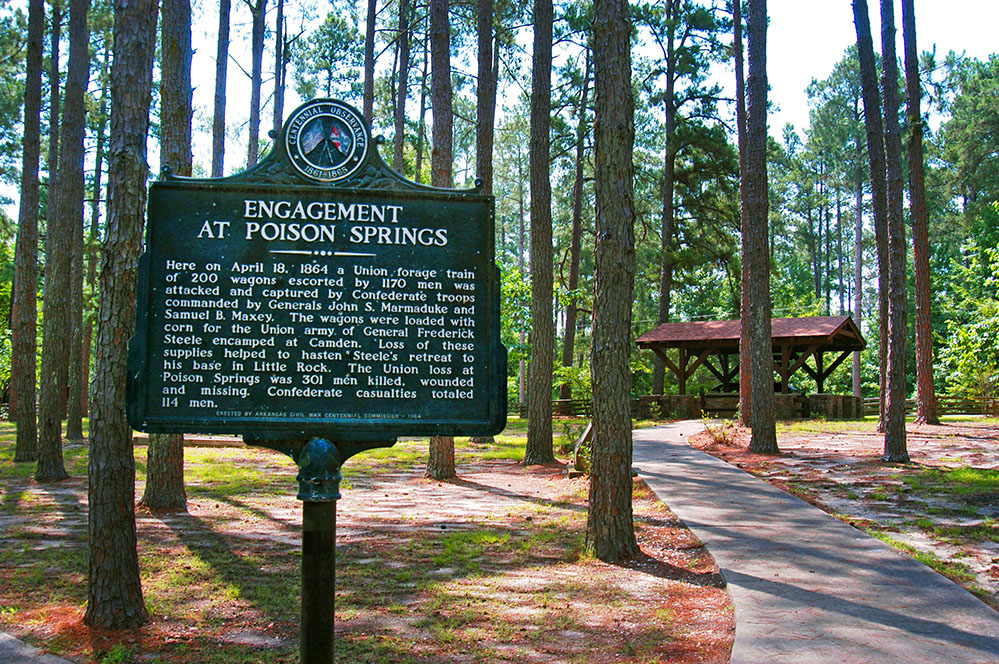 Poison Springs Battlefield sign Black sign in a forest.