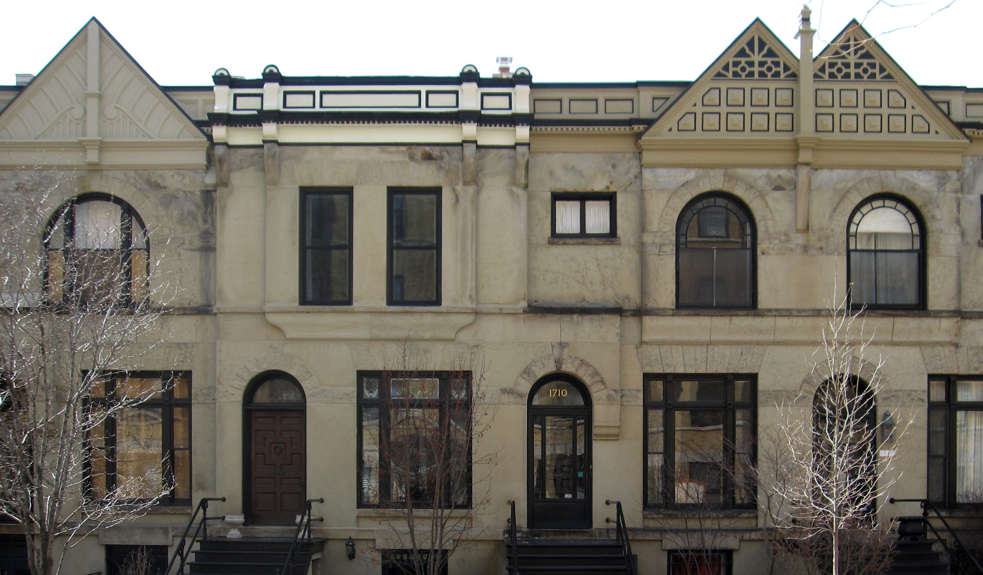 Three-story stone town homes with black windows.