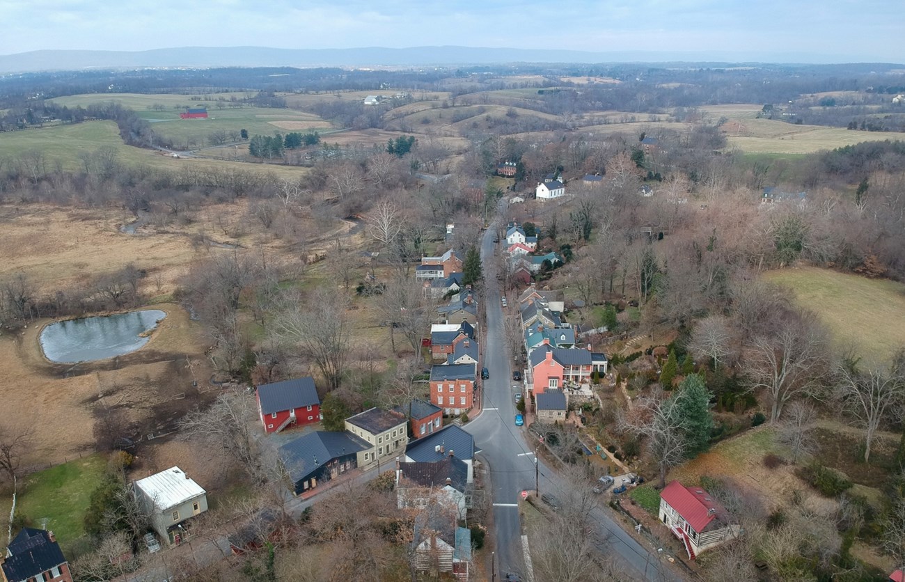 Color aerial photo showing the main intersection in the village of Waterford with many houses lining the streets and sprawling fields, trees, and farmsteads stretching to the outer limits of the image.