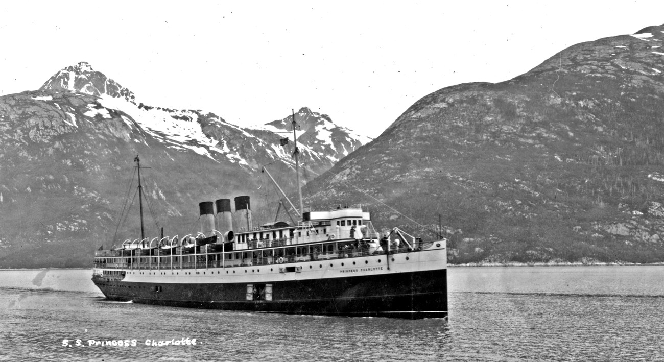 A photo of a ship with mountains in the background