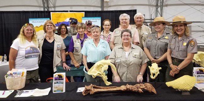 A group of people gather around a table of fossil displays at an event.