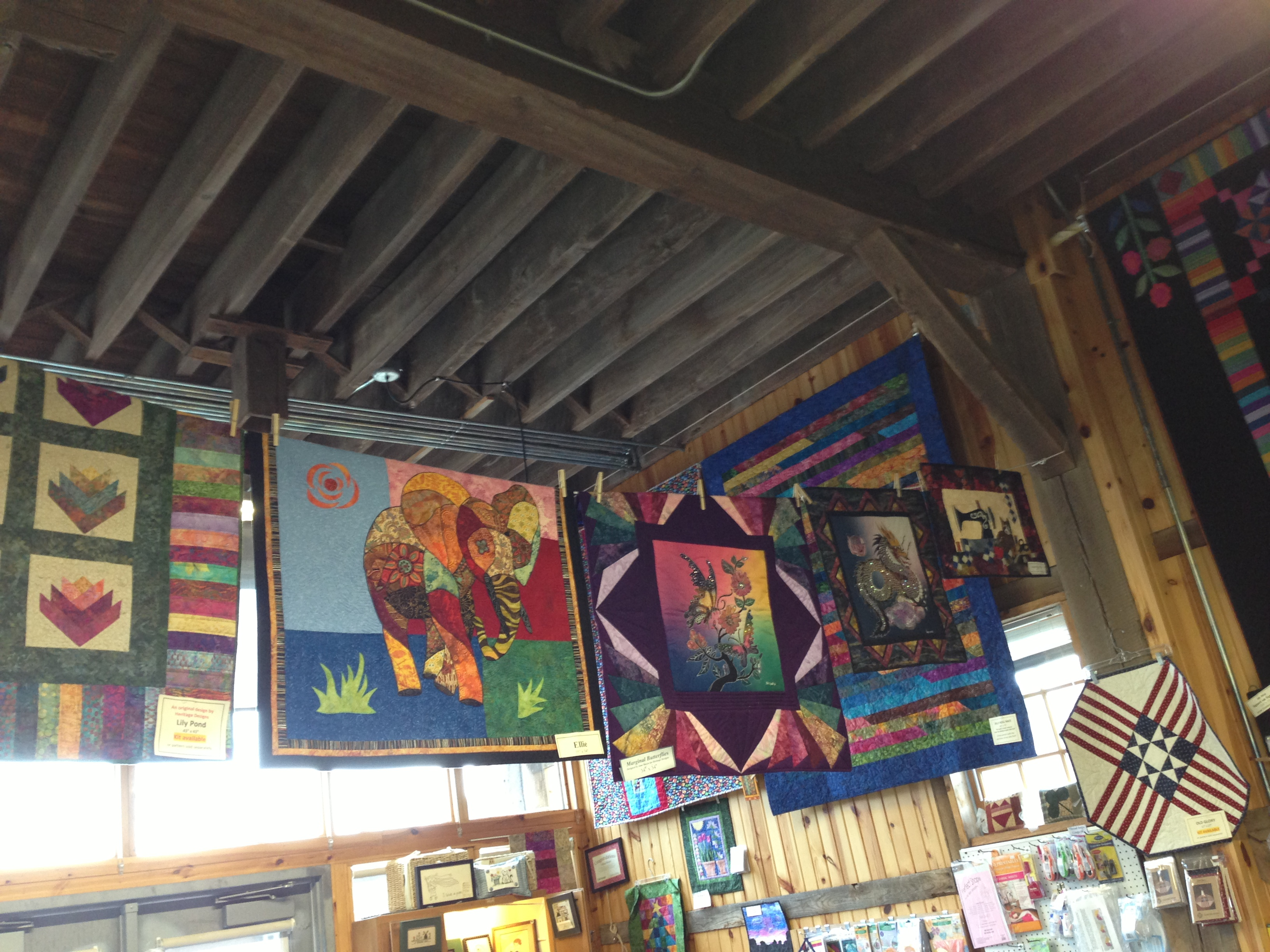 Interior of adapted quilt store Multi-colored hanging on the walls and from the wooden rafters.