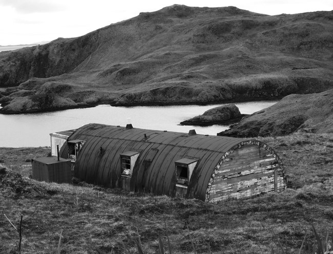 A rectangular building with a metal round or arched roof. The metal is rusting.