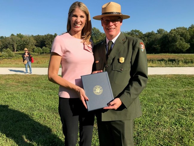 A woman and a man in uniform hold a document