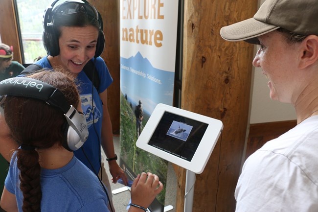 Wearing headphones, a mother and daughter try to "guess that sound" in a listening activity.