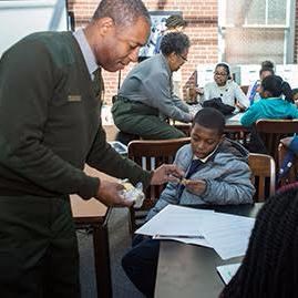 Ranger Theodore Johnson with students African American male ranger teaches a student at a table.