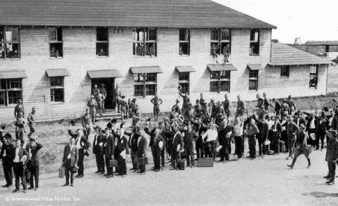 Recruits Arrive at Camp Lee Men in uniform and civilian clothes stand outside a military buliding