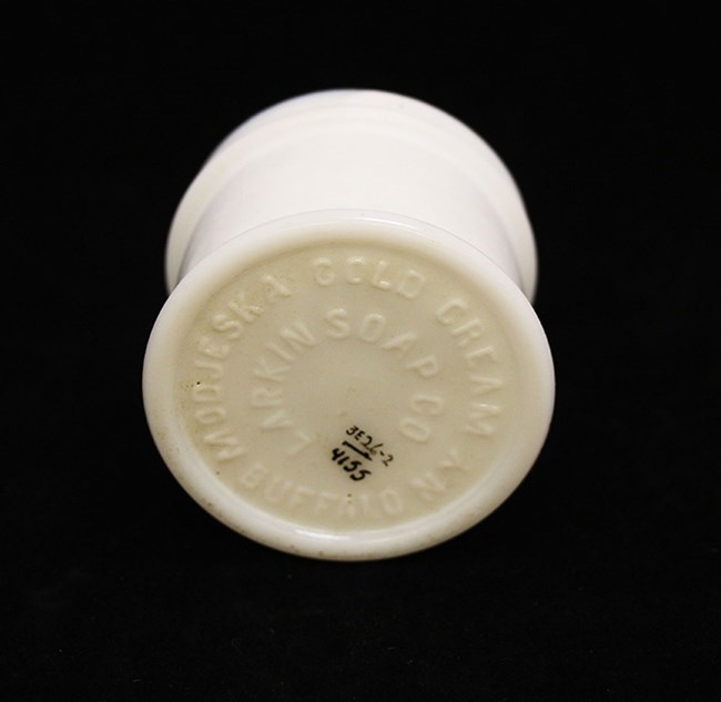 A small ceramic knob-shaped object with “MODJESKA COLD CREAM, BUFFALO, NY” and “LARKING SOAP CO” embossed on it.