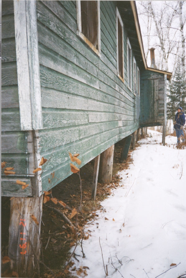 Green building on stilts in the snow.