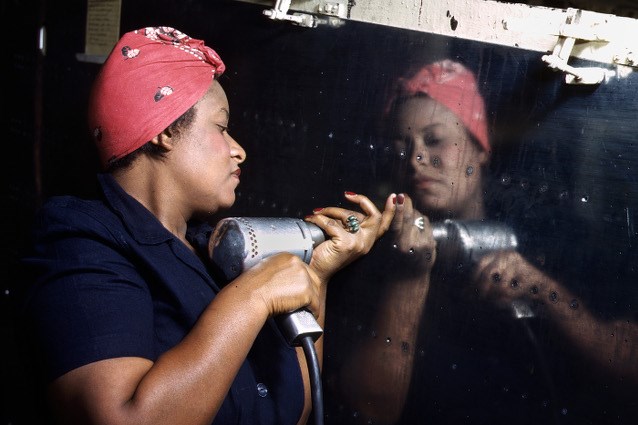 An African American "Rosie" installing rivets on a war plane.