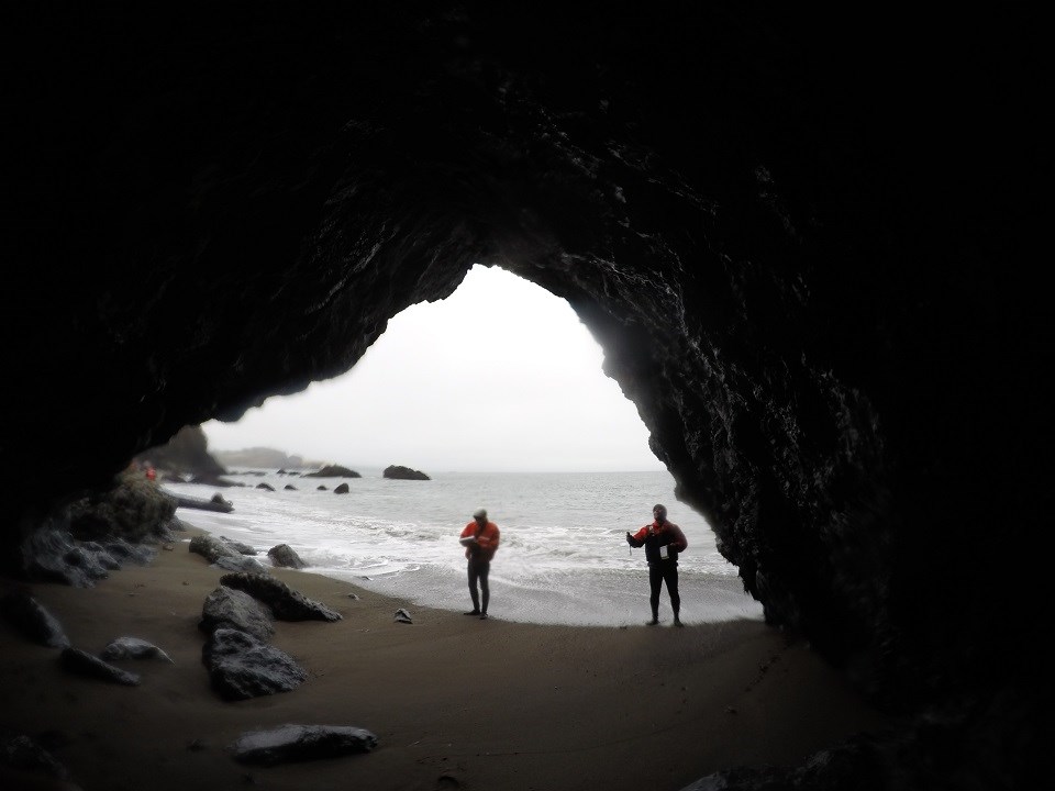 Two National Park Service scientists standing in the mouth of a sea cave