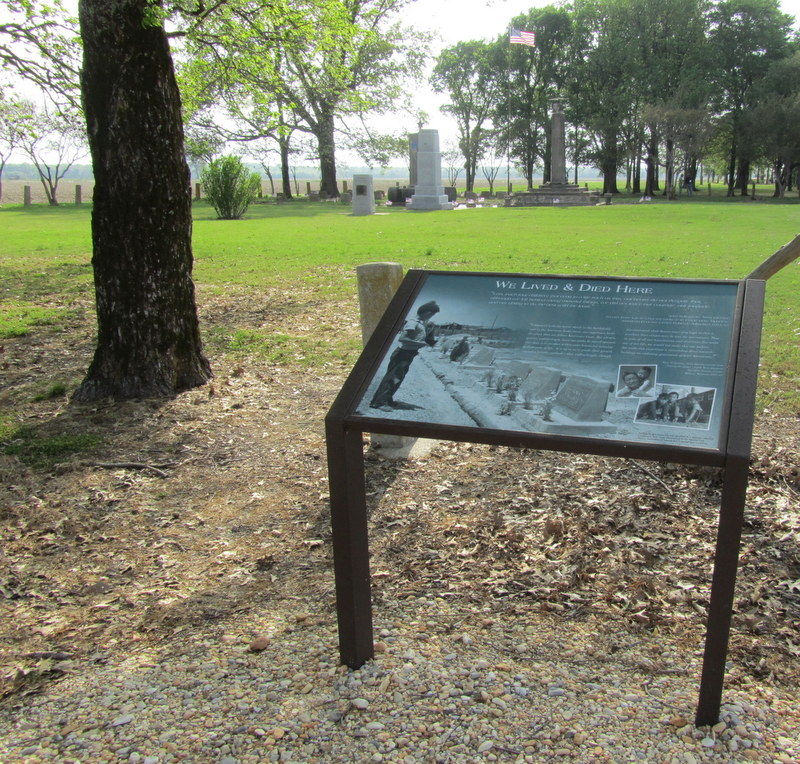 Green field of trees and headstones with a information plaque.