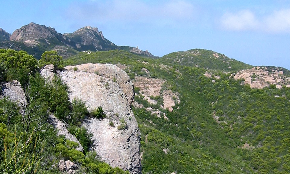 Green sloped mountains dotted with rocky outcroppings under blue skies.