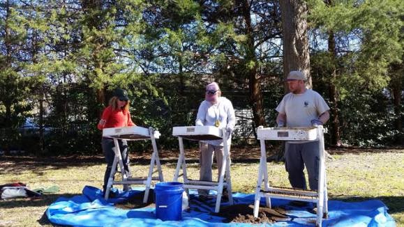SEAC osteologists Katie Miyar (far left) and Ian Pawn (far right), and public outreach coordinator Thadra Stanton (center) screening soil from the excavation units. SEAC osteologists Katie Miyar (far left) and Ian Pawn (far right), and public outreach coordinator Thadra Stanton (center) screening soil from the excavation units.